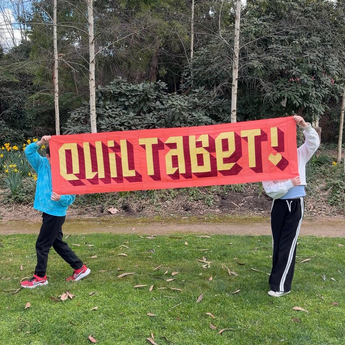Kids holding quiltabet quilt banner
